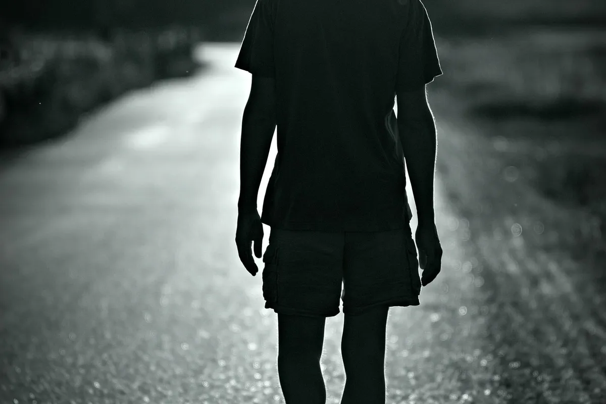 Silhouette of a person walking along a wet path